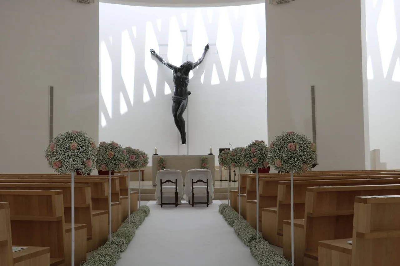 Navata di una chiesa moderna con composizioni bianche sulle panche
