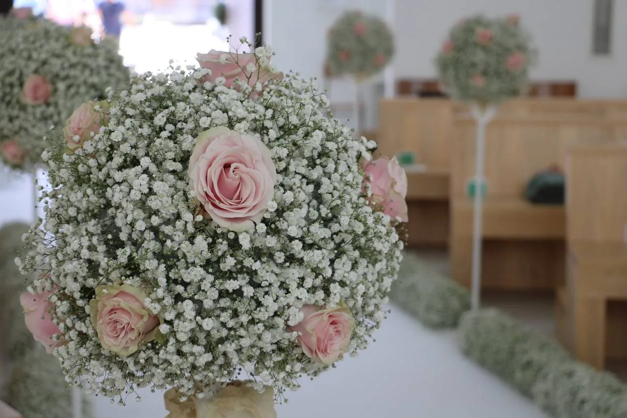 Sfera di gypsophila e rose rosa appesa a una panca di chiesa