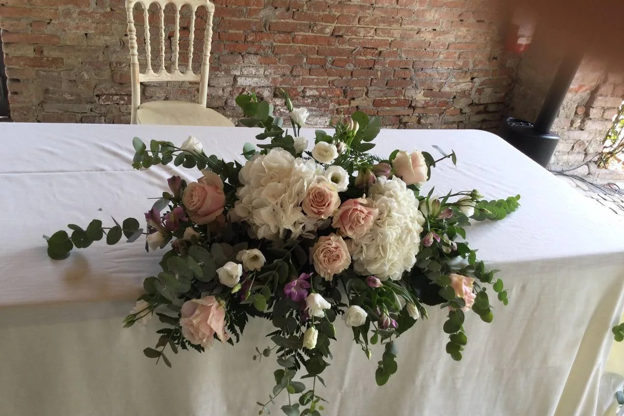 Composizione di rose, ortensie e verde su un tavolo con tovaglia bianca